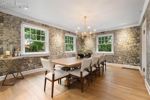 dining area with light hardwood / wood-style floors, ornamental molding, and a chandelier