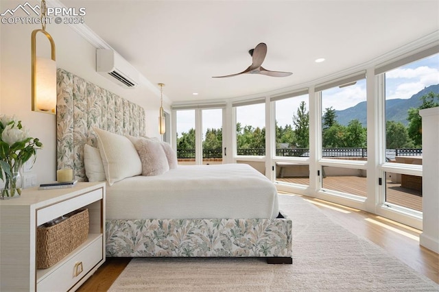 bedroom featuring ceiling fan, an AC wall unit, a mountain view, hardwood / wood-style floors, and ornamental molding