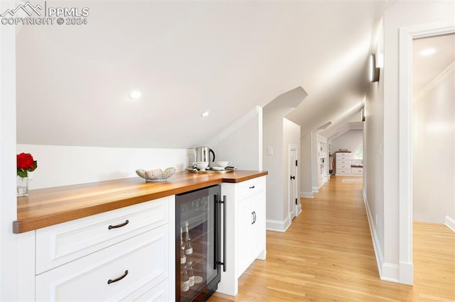 bar featuring wine cooler, white cabinets, wooden counters, and lofted ceiling