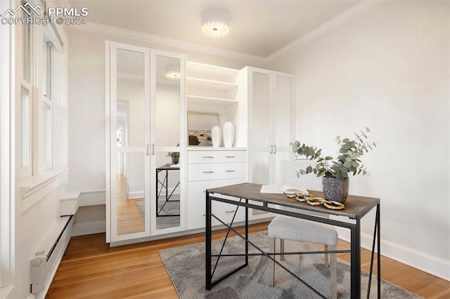 home office featuring crown molding, baseboard heating, and light hardwood / wood-style flooring