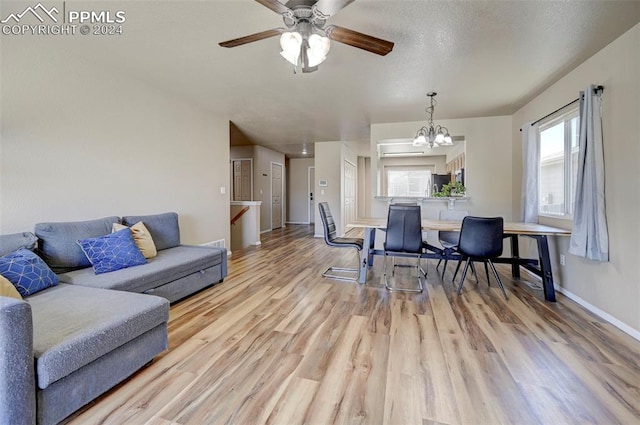 living room featuring a textured ceiling, light hardwood / wood-style flooring, and ceiling fan with notable chandelier