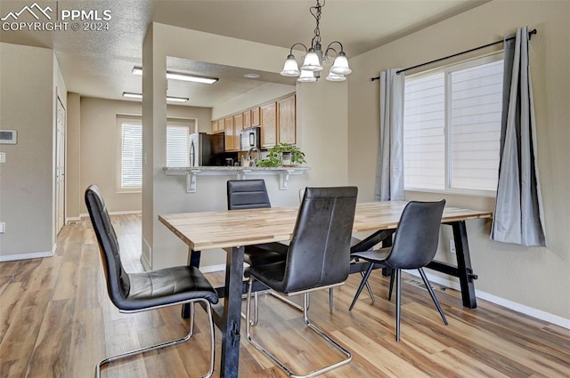 dining room with a textured ceiling, light hardwood / wood-style flooring, and an inviting chandelier