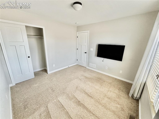 unfurnished bedroom featuring light carpet and a closet