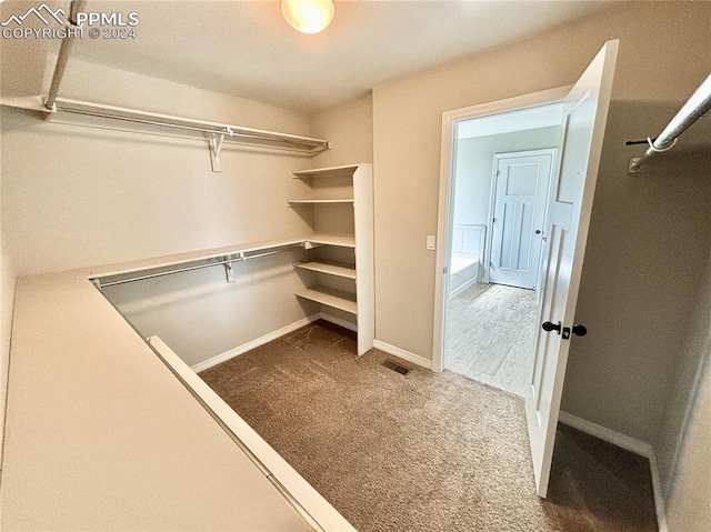 walk in closet featuring dark carpet