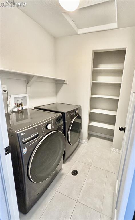 washroom with light tile patterned flooring and washing machine and dryer