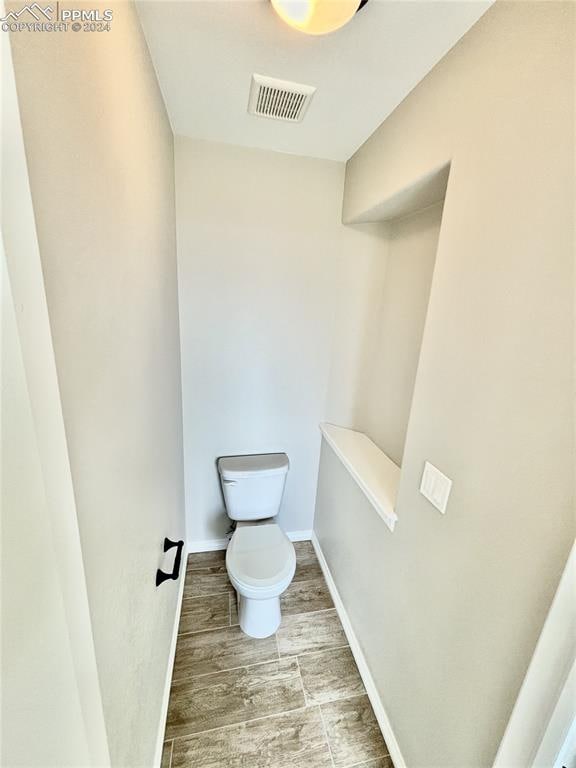 bathroom featuring hardwood / wood-style flooring and toilet