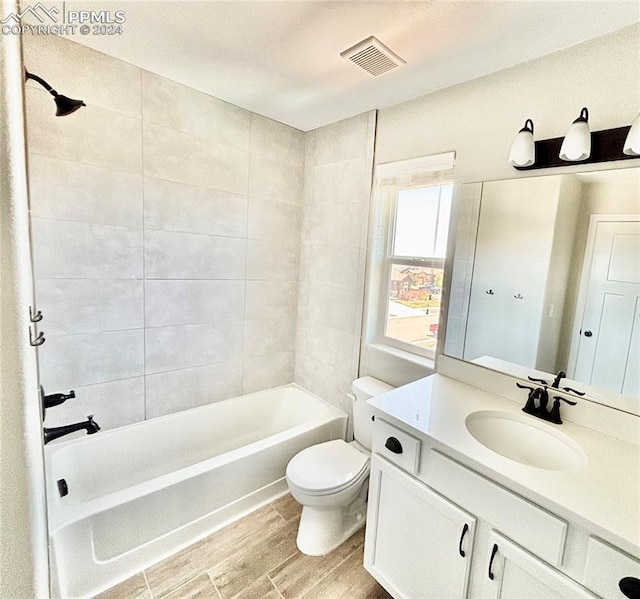 full bathroom featuring hardwood / wood-style floors, toilet, vanity, and tiled shower / bath