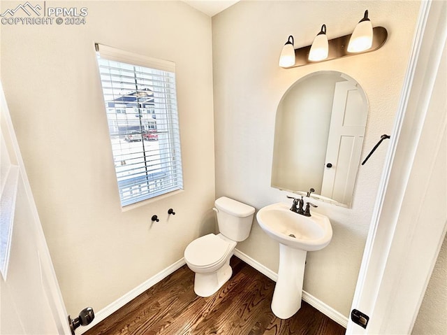 bathroom with toilet, wood-type flooring, and a healthy amount of sunlight