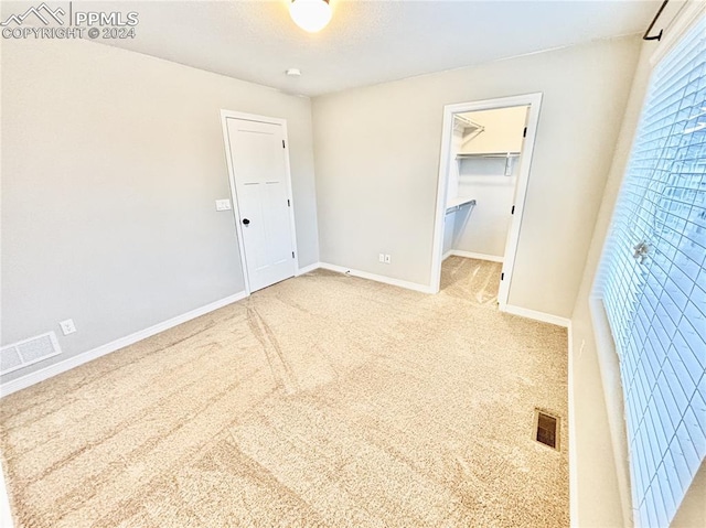 unfurnished bedroom with a closet, carpet flooring, and a walk in closet