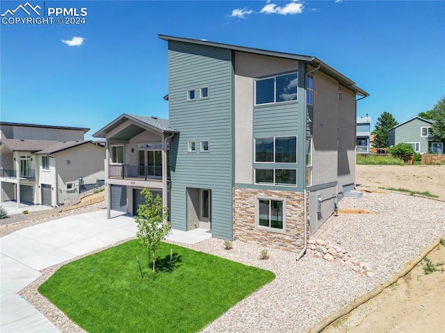 back of house with a garage, a yard, and a balcony