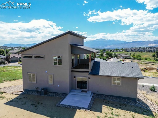 rear view of property with a balcony and a mountain view