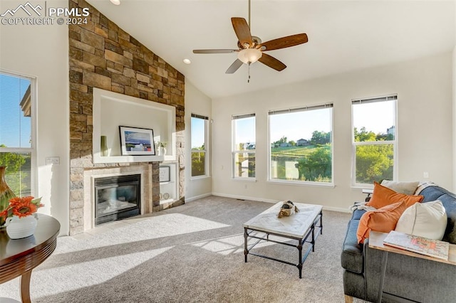 carpeted living room featuring ceiling fan, a stone fireplace, and vaulted ceiling