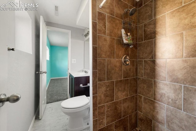 bathroom with a tile shower, vanity, and toilet