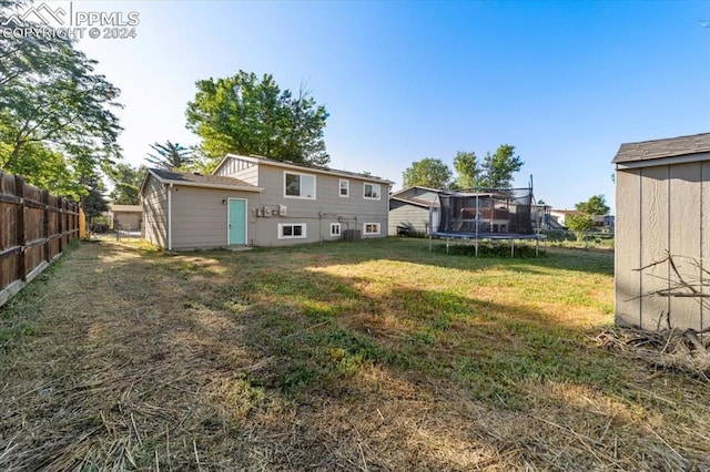 back of property featuring a yard and a trampoline