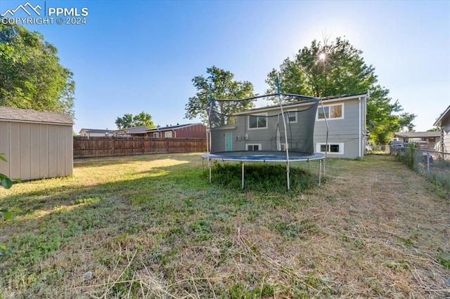 back of house with a shed, a trampoline, and a yard