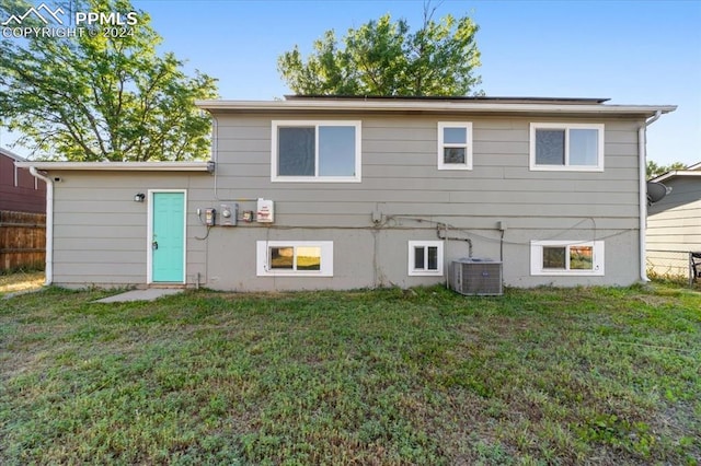 rear view of house featuring cooling unit and a yard