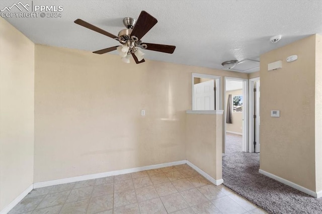 carpeted spare room with ceiling fan and a textured ceiling