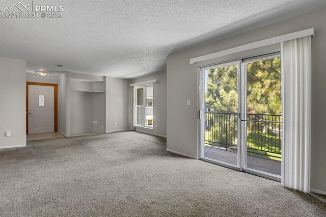 unfurnished living room with carpet floors and a textured ceiling