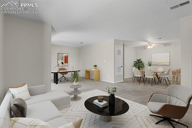 living room featuring light carpet, ceiling fan, and a textured ceiling