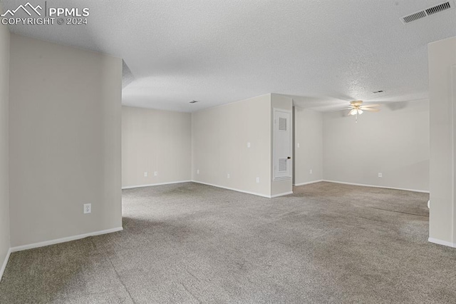 spare room with a textured ceiling, ceiling fan, and carpet