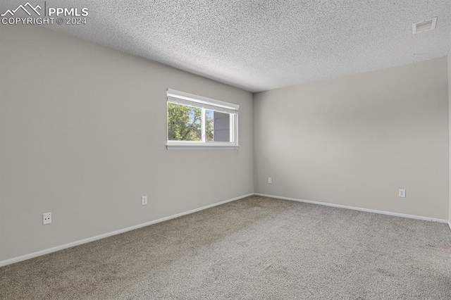 spare room with a textured ceiling and carpet