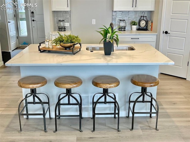 kitchen featuring tasteful backsplash, white cabinetry, and a center island with sink