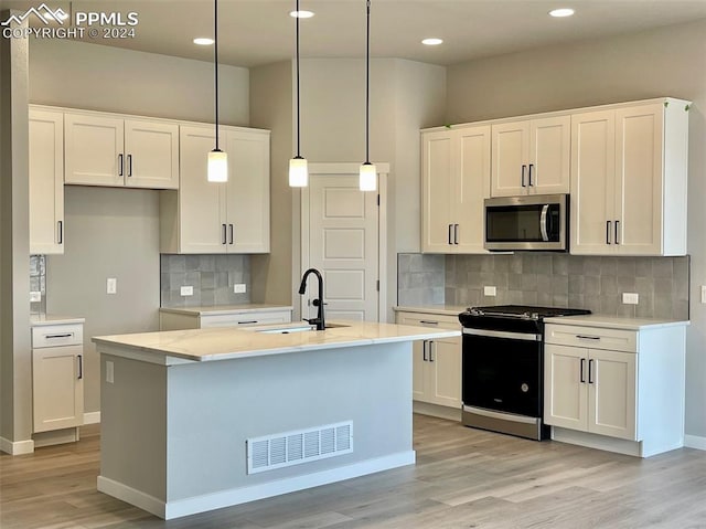 kitchen featuring hanging light fixtures, white cabinets, and stainless steel appliances