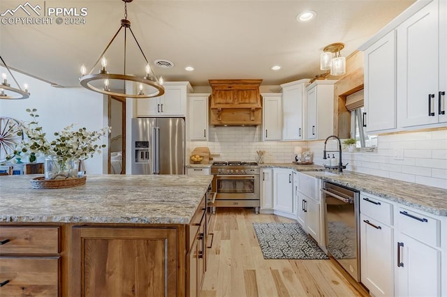 kitchen featuring light hardwood / wood-style flooring, custom range hood, light stone counters, backsplash, and premium appliances