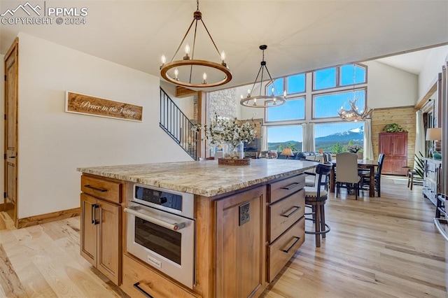 kitchen featuring a center island, light hardwood / wood-style floors, stainless steel oven, and decorative light fixtures