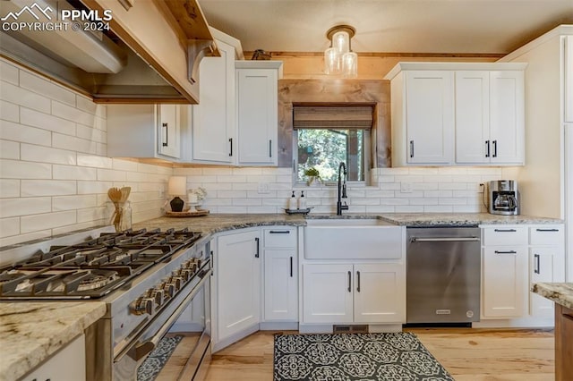 kitchen with light hardwood / wood-style floors, tasteful backsplash, custom exhaust hood, white cabinetry, and appliances with stainless steel finishes