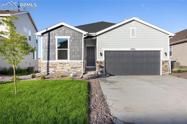 view of front facade with a garage, central AC unit, and a front lawn