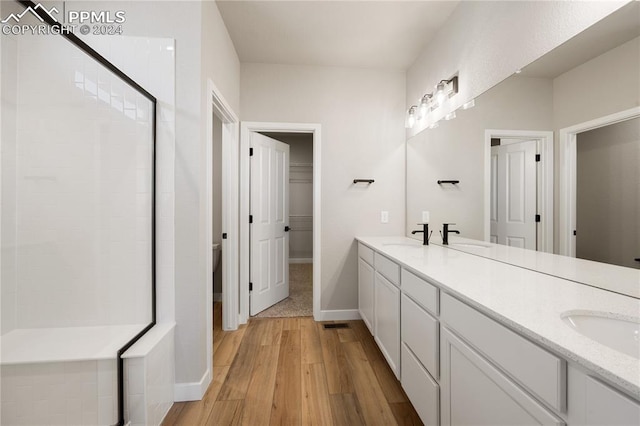 bathroom featuring vanity, hardwood / wood-style floors, walk in shower, and toilet