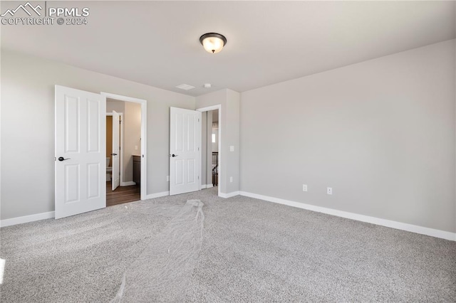 unfurnished bedroom with carpet floors and ensuite bath