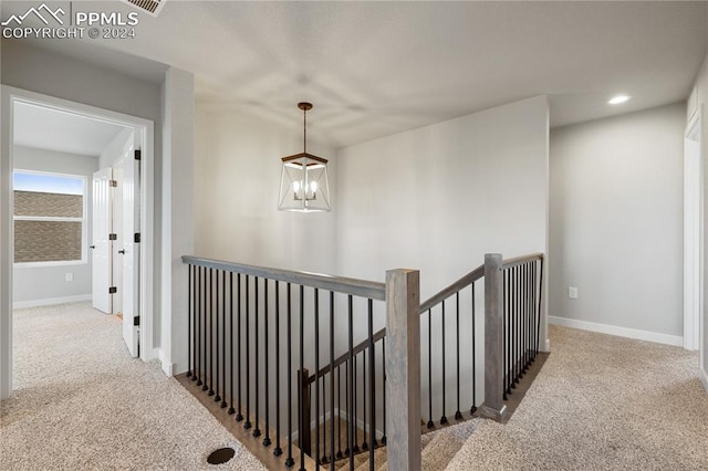 hallway with a chandelier and carpet flooring