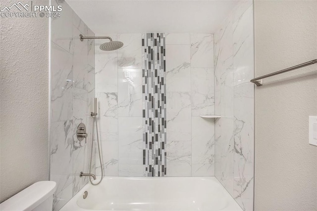 bathroom featuring tiled shower / bath and toilet