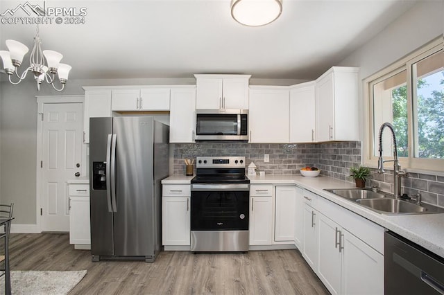 kitchen featuring stainless steel appliances, light hardwood / wood-style floors, decorative light fixtures, and sink