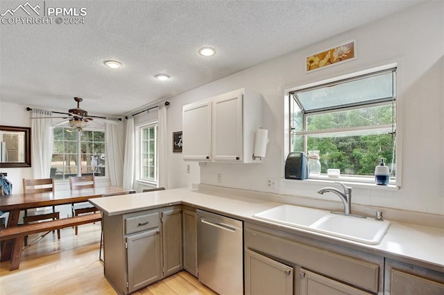 kitchen with a textured ceiling, sink, kitchen peninsula, stainless steel dishwasher, and light hardwood / wood-style flooring