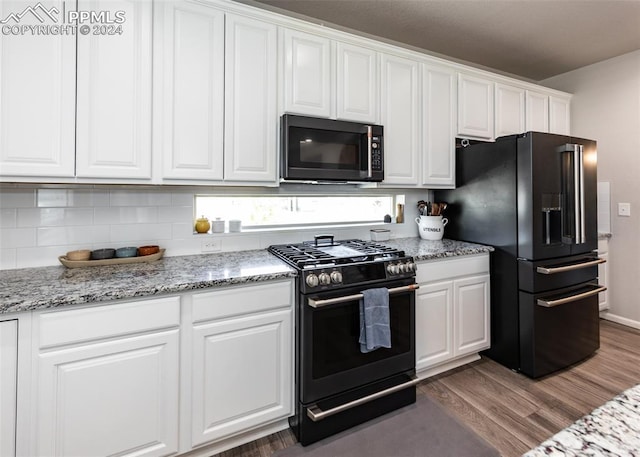 kitchen with light stone countertops, white cabinetry, dark hardwood / wood-style flooring, and black appliances