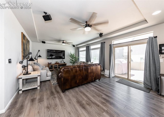 living room featuring a tray ceiling, ceiling fan, and wood-type flooring