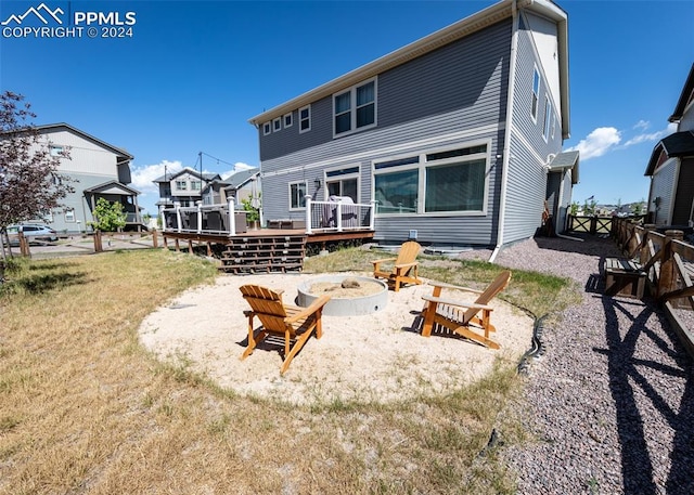 back of property featuring a fire pit, a deck, and a yard