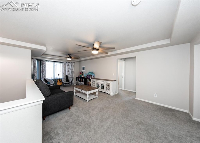 carpeted living room with a tray ceiling and ceiling fan