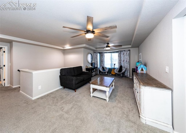 living room featuring ceiling fan, a raised ceiling, and light colored carpet