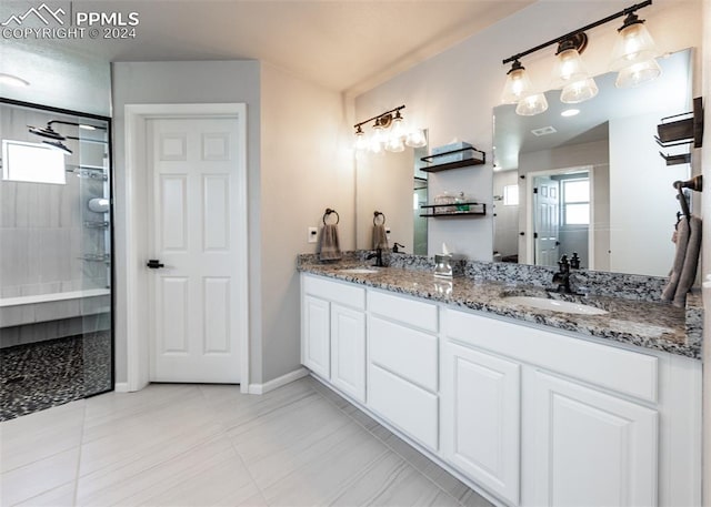 bathroom with tile patterned flooring, a tile shower, and vanity