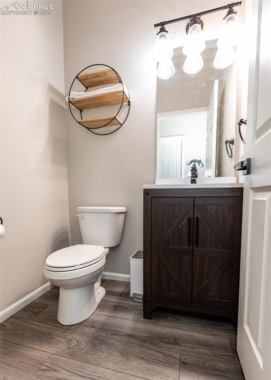 bathroom with hardwood / wood-style floors, vanity, and toilet