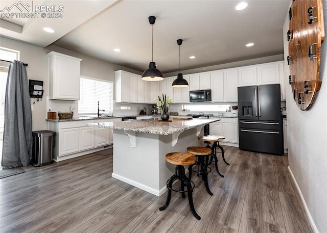 kitchen with dark hardwood / wood-style flooring, a center island, white cabinets, and black appliances