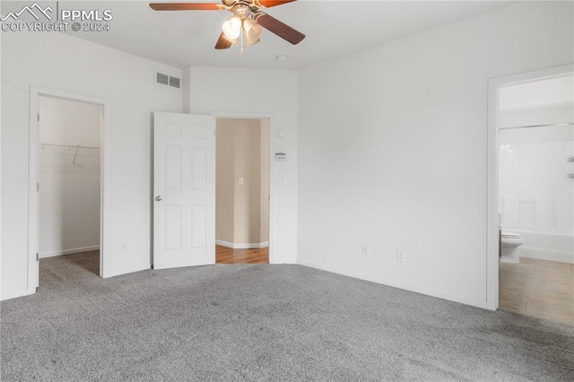 unfurnished bedroom featuring carpet flooring, a walk in closet, ensuite bathroom, ceiling fan, and a closet