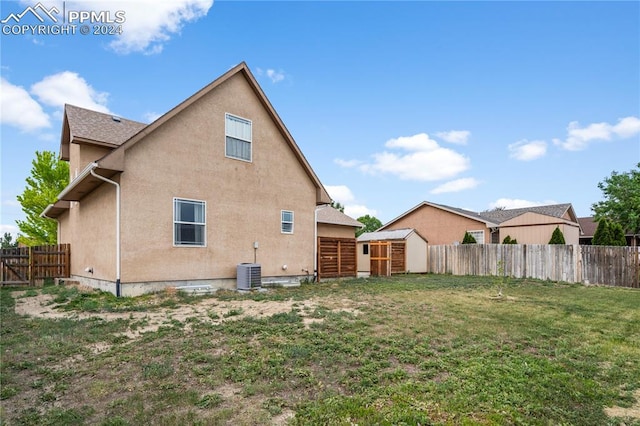 rear view of property with a yard, a storage shed, and central air condition unit