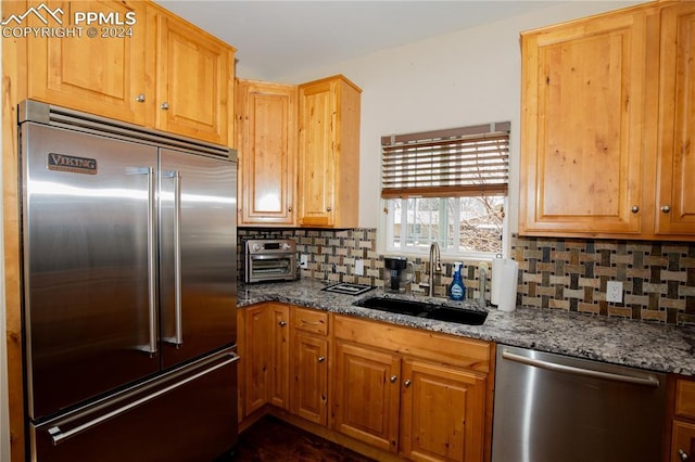 kitchen featuring stone countertops, sink, stainless steel appliances, and tasteful backsplash