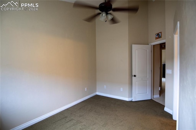 spare room featuring dark colored carpet and ceiling fan