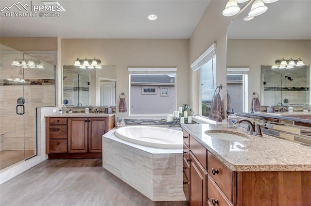 bathroom with vanity, wood-type flooring, a notable chandelier, and shower with separate bathtub